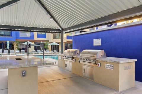 A grill with a caution sign on it is in front of a blue wall.