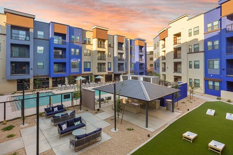 A modern apartment complex with a pool and outdoor seating area.