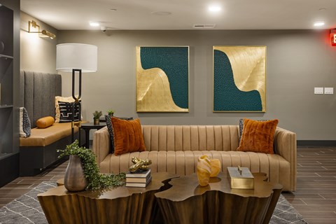 A living room with a beige couch, a coffee table, and two abstract paintings on the wall.