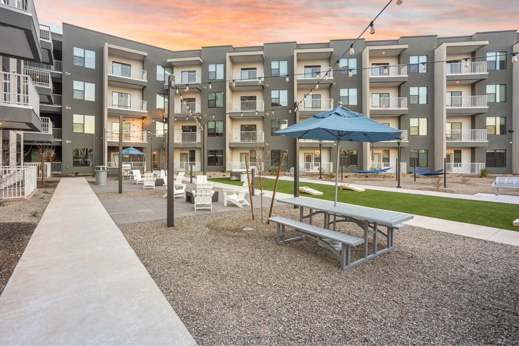 A sunny day at the apartment complex with a blue umbrella and picnic table.