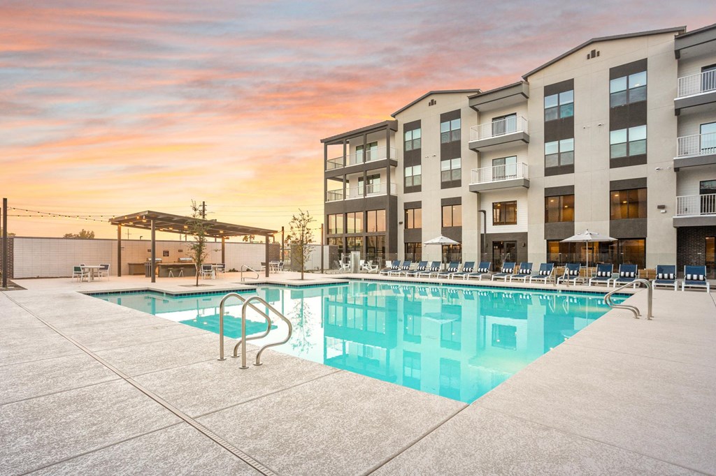 A large swimming pool is surrounded by apartment buildings.