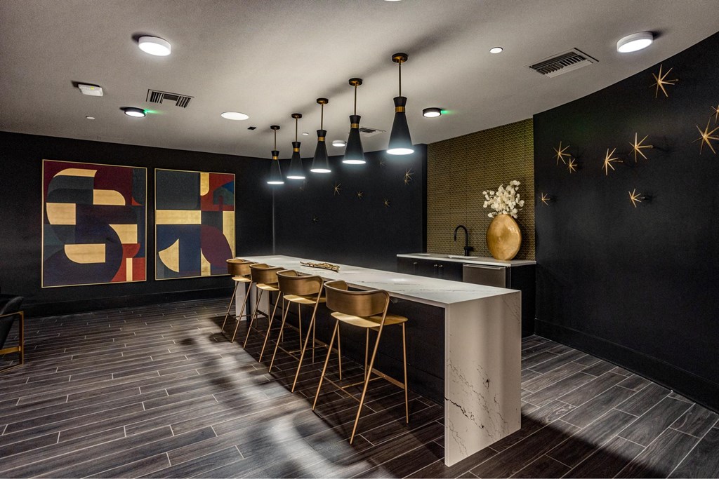 A modern bar with a white counter and wooden stools.