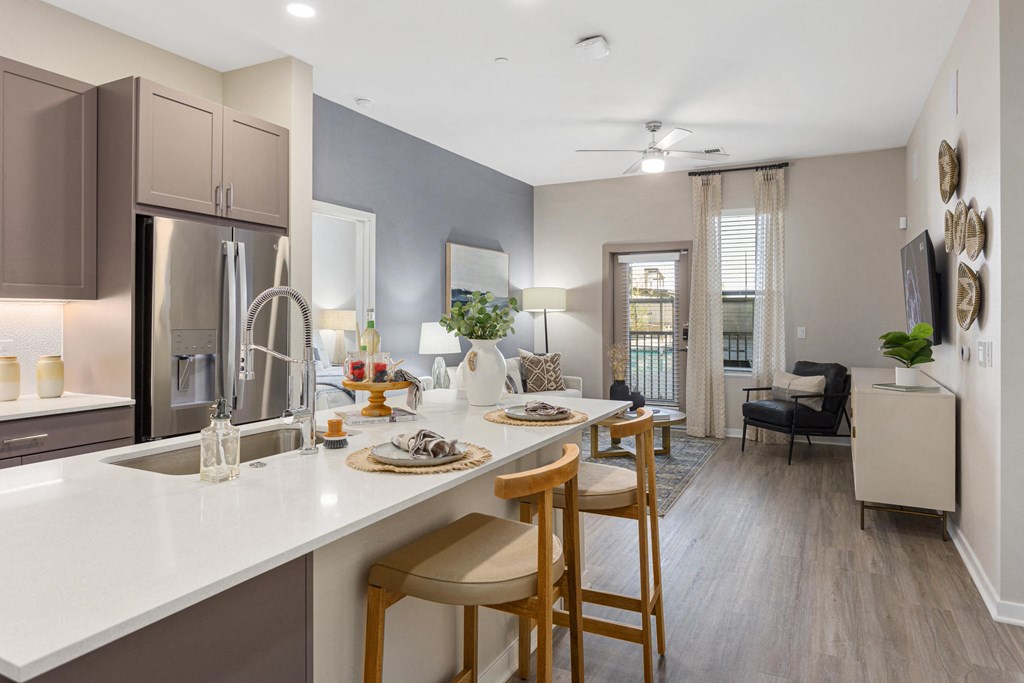 a kitchen with an island and stools in front of a living room