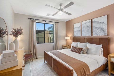 A bedroom with a large bed and a view of a building outside the window.