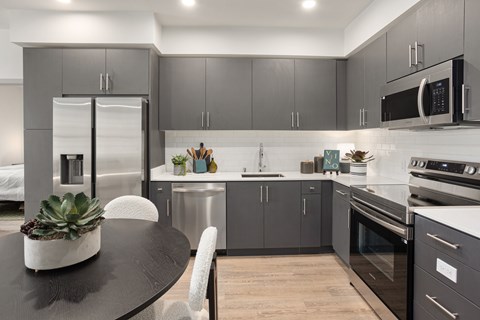 A modern kitchen with a black table and grey cabinets.