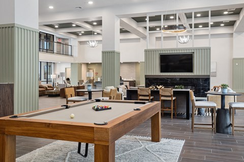 A pool table is in the middle of a room with a fireplace and a television.