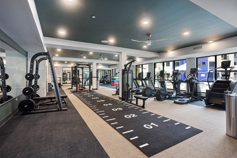 A gym with a variety of equipment including treadmills, weights, and exercise machines.
