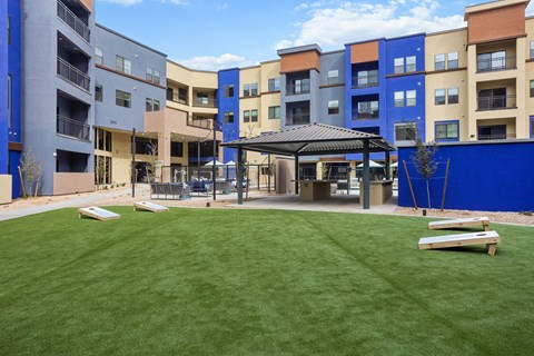 A grassy area in front of a building with a blue wall on the right side.