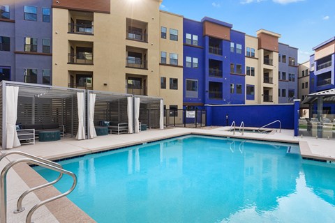 A swimming pool in front of a building with a blue sky in the background.