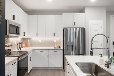 A modern kitchen with white cabinets and stainless steel appliances.