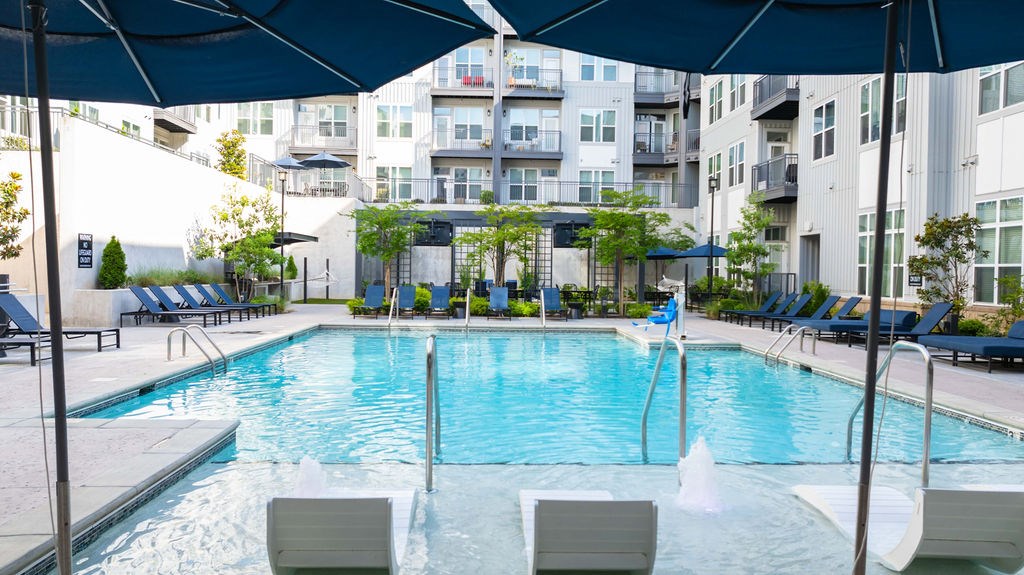 A large outdoor swimming pool with lounge chairs and umbrellas.