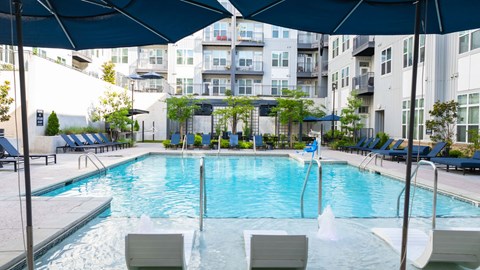 A large outdoor swimming pool with lounge chairs and umbrellas.