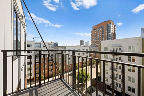A balcony with a metal railing overlooks a cityscape.