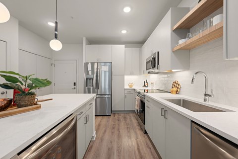 A modern kitchen with stainless steel appliances and wooden floors.