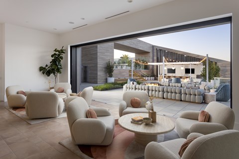 A modern living room with white furniture and a large window overlooking a patio.