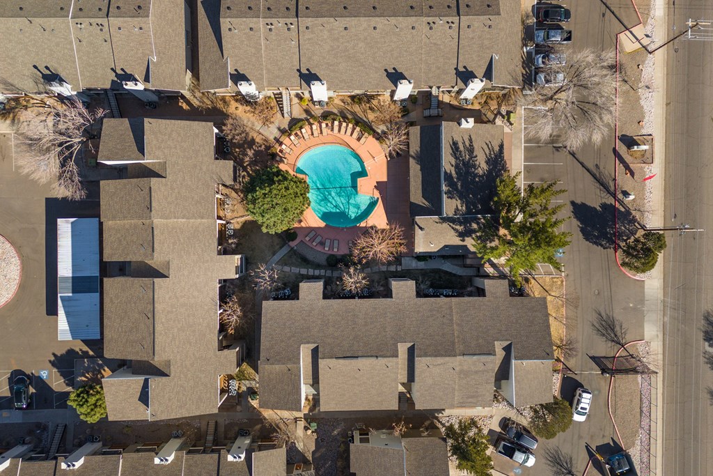 An aerial view of a swimming pool surrounded by trees and buildings.