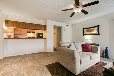 A living room with a beige couch and a ceiling fan.