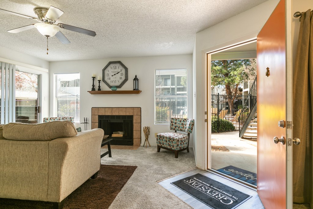 A living room with a beige couch, a fireplace, and a ceiling fan.