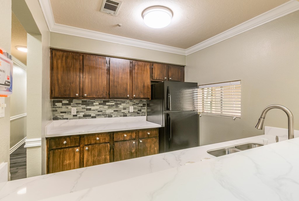 A kitchen with a black refrigerator and wooden cabinets.