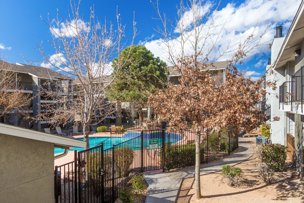 A pool surrounded by a fence and trees.