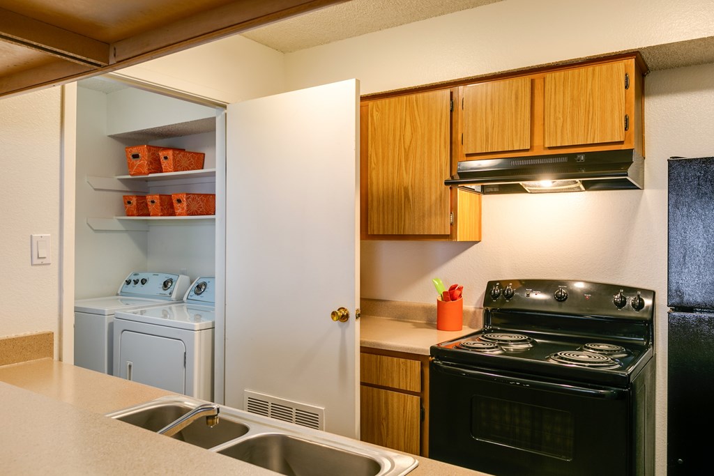 A kitchen with a black stove and wooden cabinets.