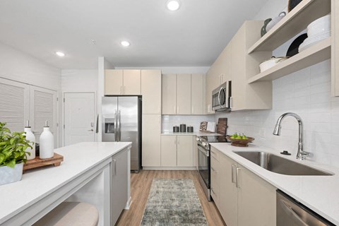 A modern kitchen with a refrigerator, microwave, and oven.