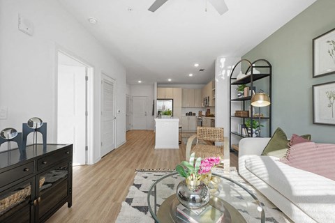 A living room with a white couch and a glass coffee table with flowers on it.