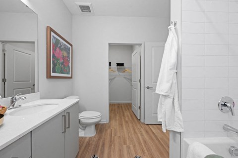 A white bathroom with a toilet, sink, and a white towel hanging on the door.