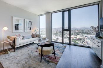 a living room with a white couch and a large window with a view of a city - Photo Gallery 54