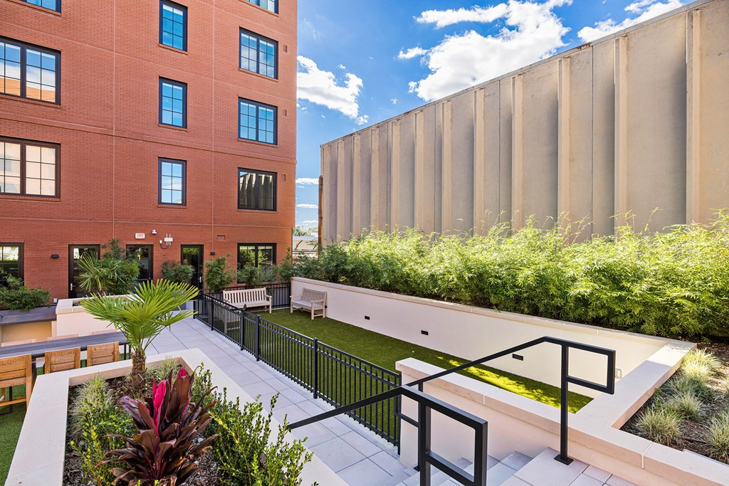 a courtyard with benches and plants and a building