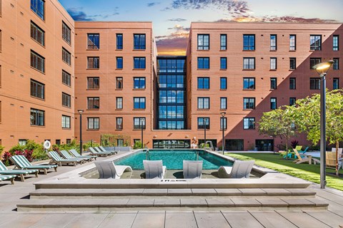 a courtyard with a pool and chairs in front of two tall buildings