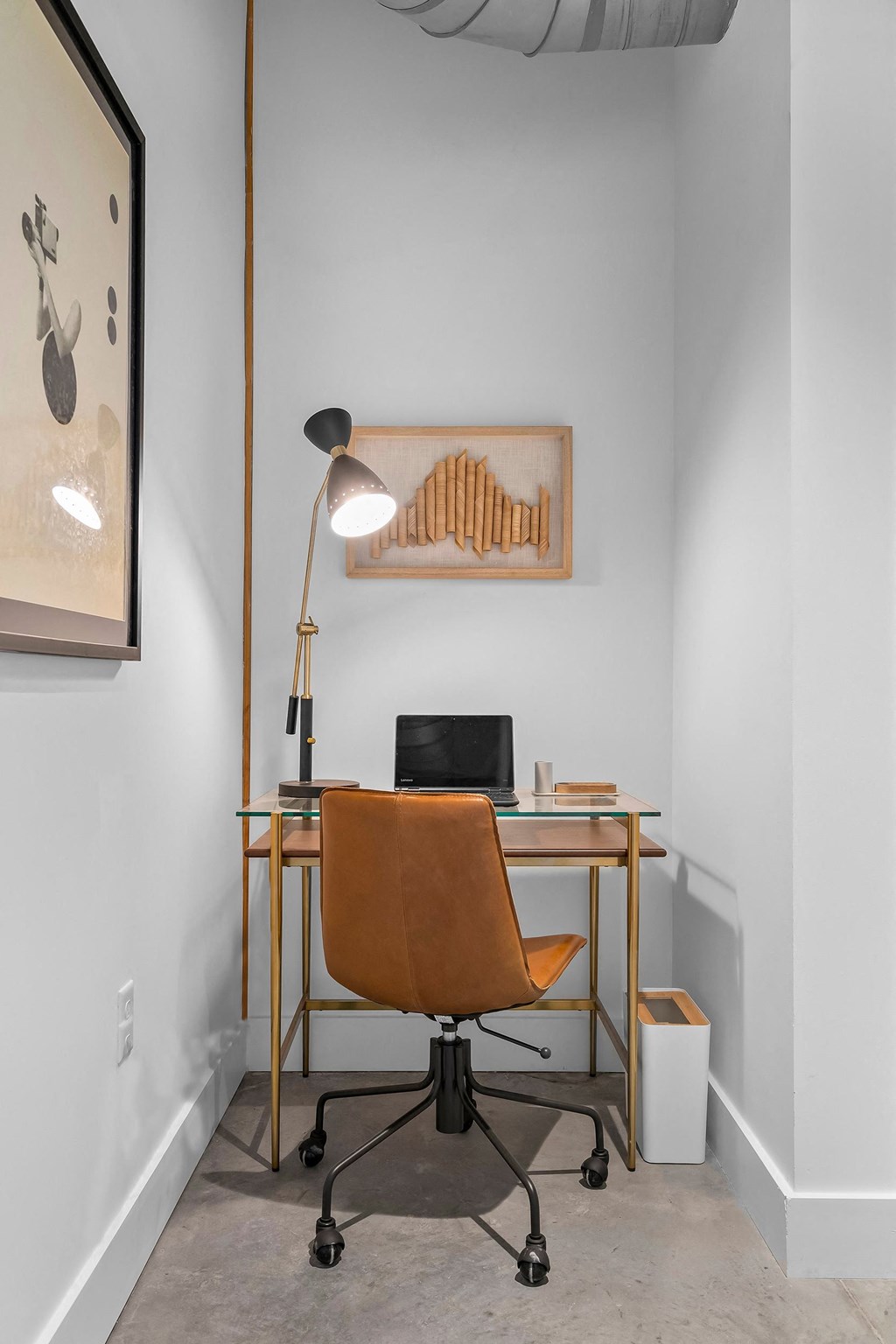 a desk with a chair and a lamp in a room with white walls