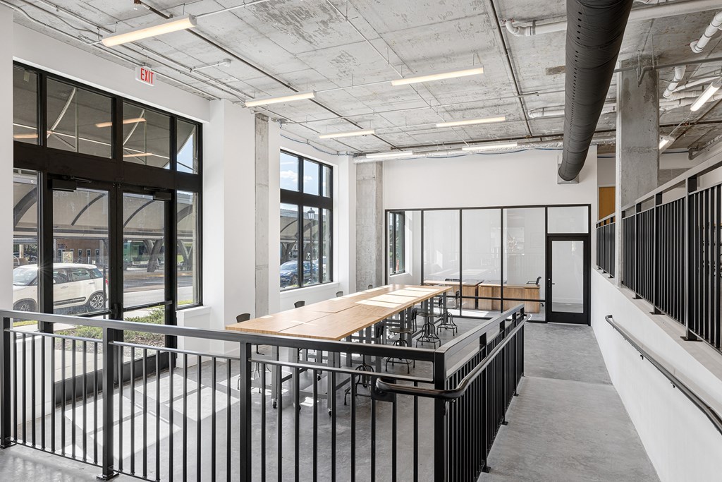 a dining room with a wooden table and chairs in a building with large windows