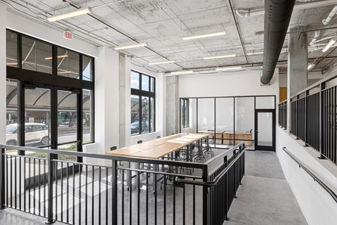 a dining room with a wooden table and chairs in a building with large windows