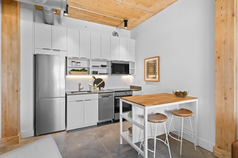 a kitchen with white cabinets and a table with three stools