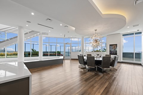 a dining room with a table and chairs and large windows