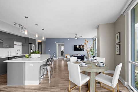 a dining room and kitchen area with a table and chairs and a large window