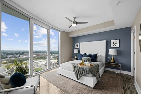 a bedroom with a large window and a bed and a ceiling fan