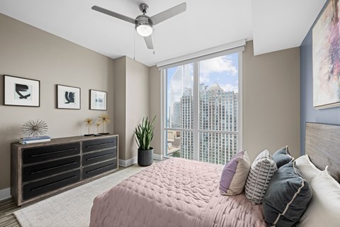 a bedroom with a large window and a bed with pillows