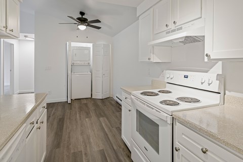 A white kitchen with a fan and a stove top oven.