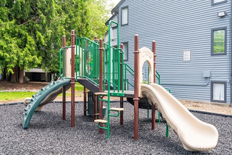 A playground with a green slide and a brown slide.