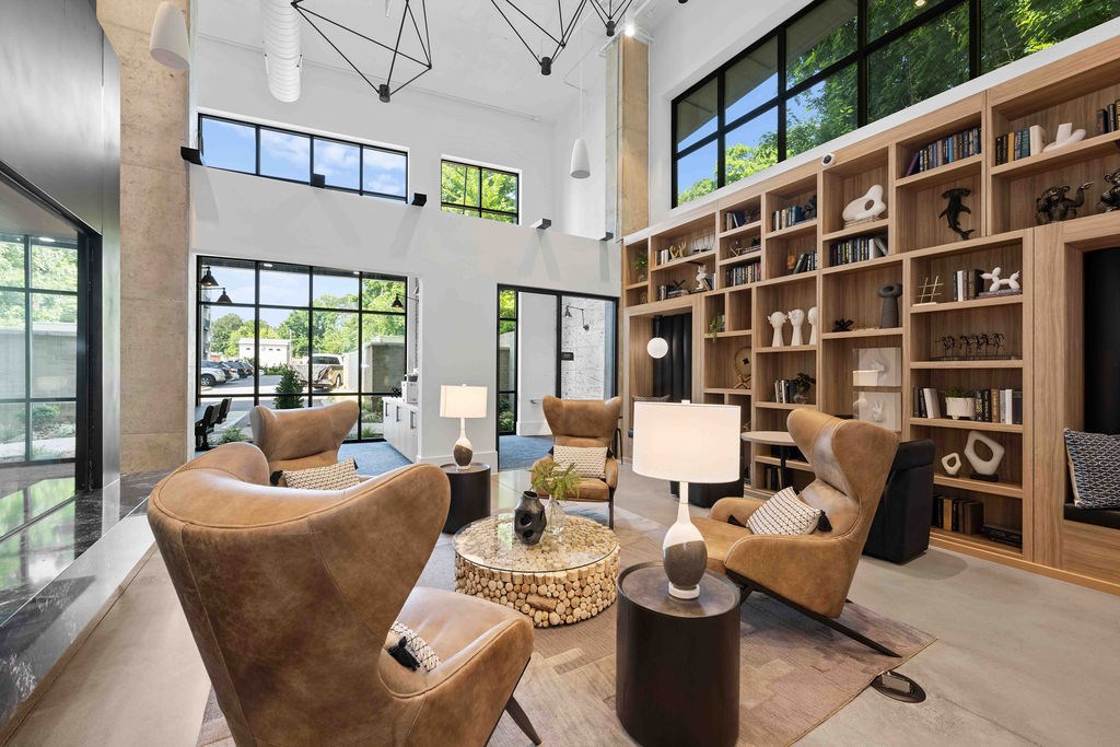 A living room with a large window, a bookshelf, and a chair.
