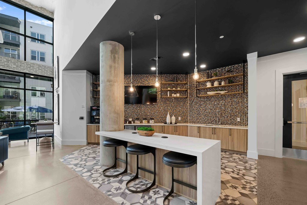 A modern kitchen with a white island and black stools.