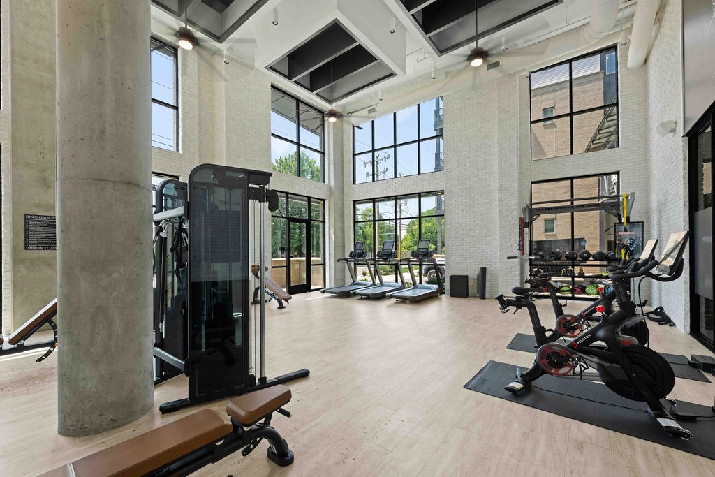 A gym with a variety of equipment including treadmills, weights, and a squat rack.