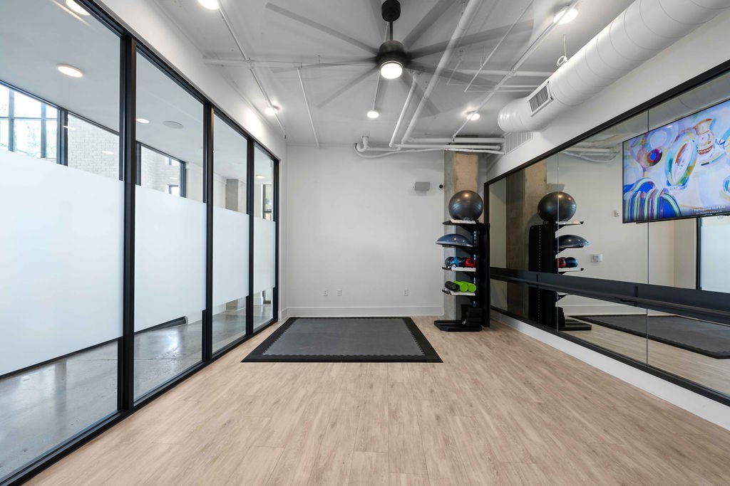 A room with a wooden floor, a black mat, and a wall with a painting.