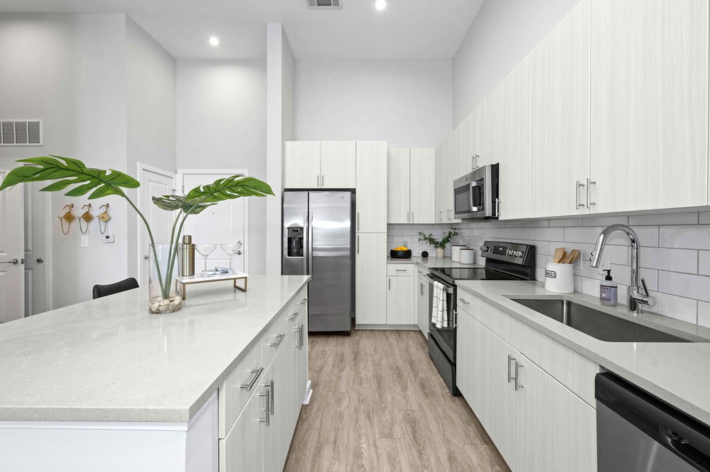 A modern kitchen with white cabinets and a marble countertop.