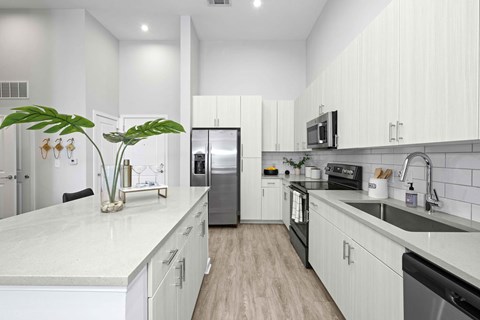 A modern kitchen with white cabinets and a marble countertop.