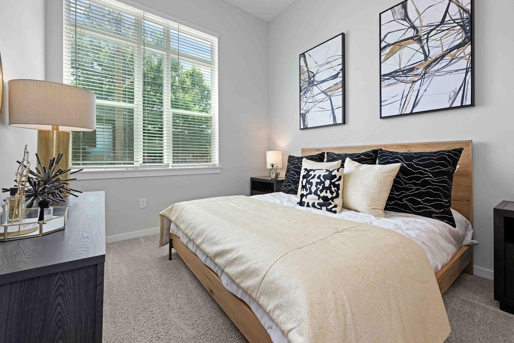 A bedroom with a large bed and two abstract paintings on the wall.