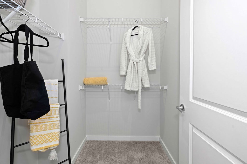A white bathroom with a towel and a robe hanging on the rack.