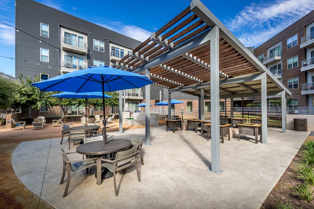 an outdoor patio with tables and umbrellas and an apartment building